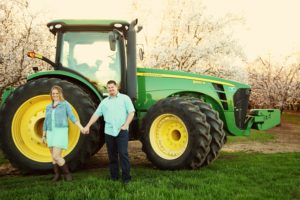 amy and derek in front of tractor in almond orchard